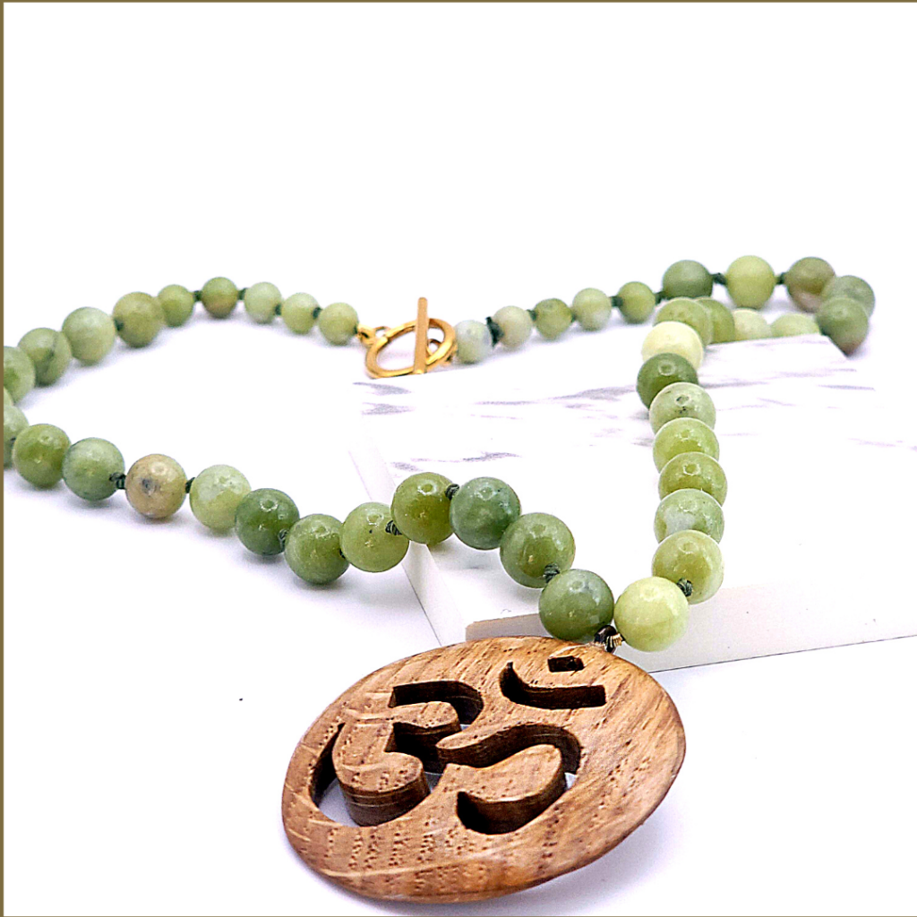 Collier artisanal en bois de chêne sculpté du symbole OM, monté sur un cordon de perles de jade nouées à la main.
