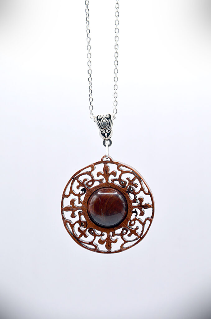 Collier artisanal en bois brun avec une pierre d’agate, sculpté selon un motif inspiré du mandala.