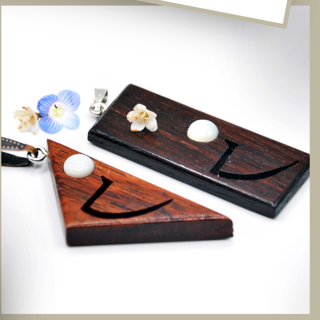 Collier artisanal en bois sculpté inspiré des hiéroglyphes égyptiens, associé à une pierre d’agate naturelle.