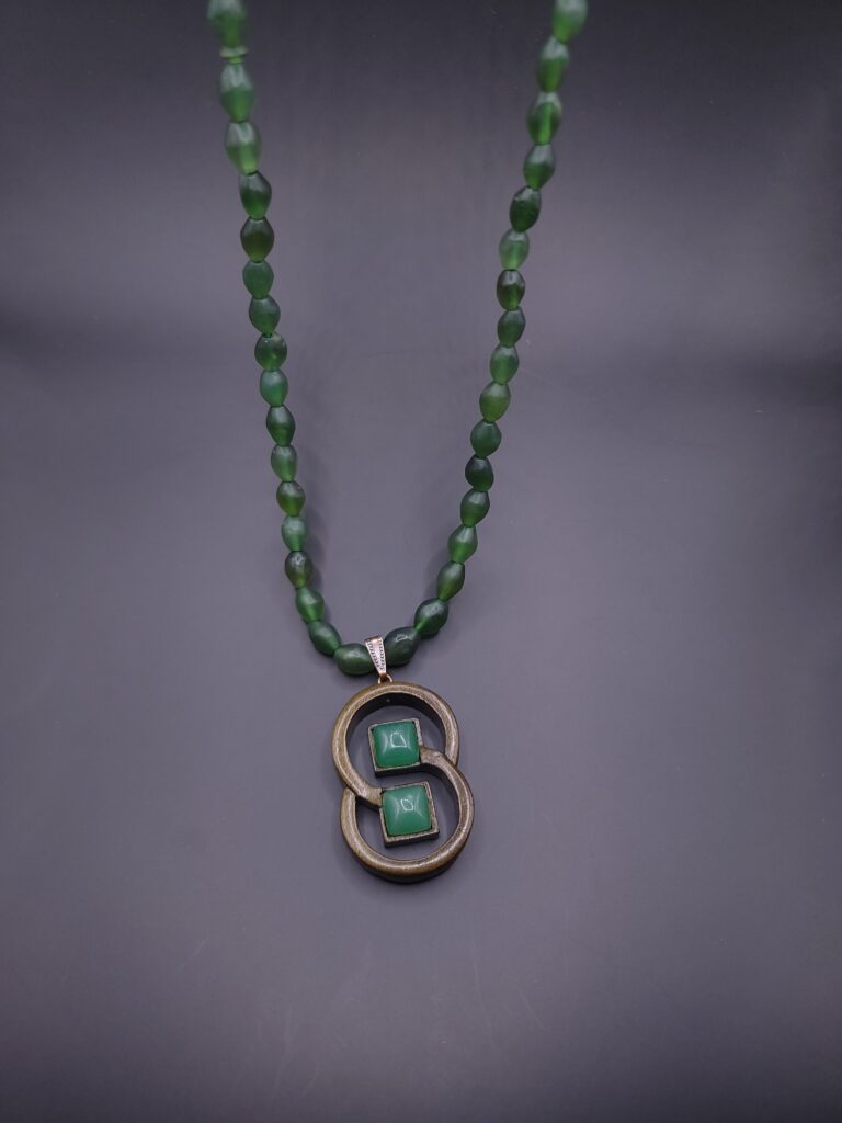 Création Artisanale de Bijoux Collier artisanal en bois avec motif de deux anneaux entrelacés, associé à une pierre de jade vert.