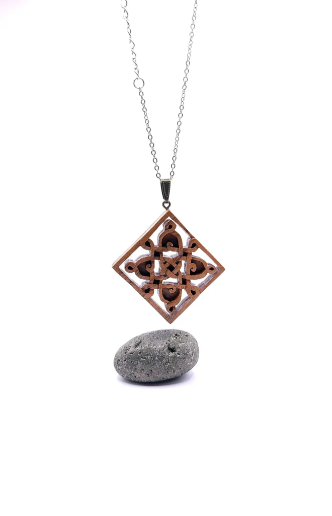 Collier artisanal en bois avec un motif carré rempli de lignes sinueuses et mystérieuses.