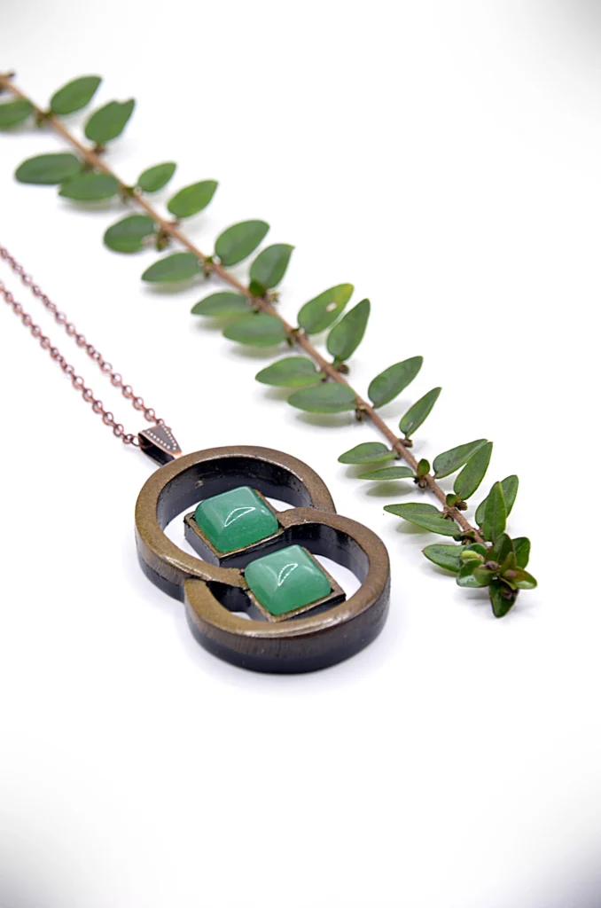 Collier artisanal en bois avec motif de deux anneaux entrelacés, associé à une pierre de jade vert.