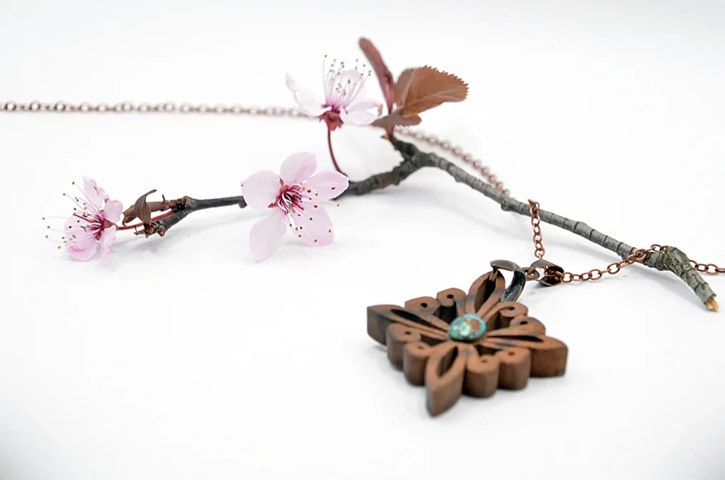 Collier artisanal en bois de noyer et pierre de turquoise, inspiré des motifs du site antique de Doura-Europos à l’époque parthe.