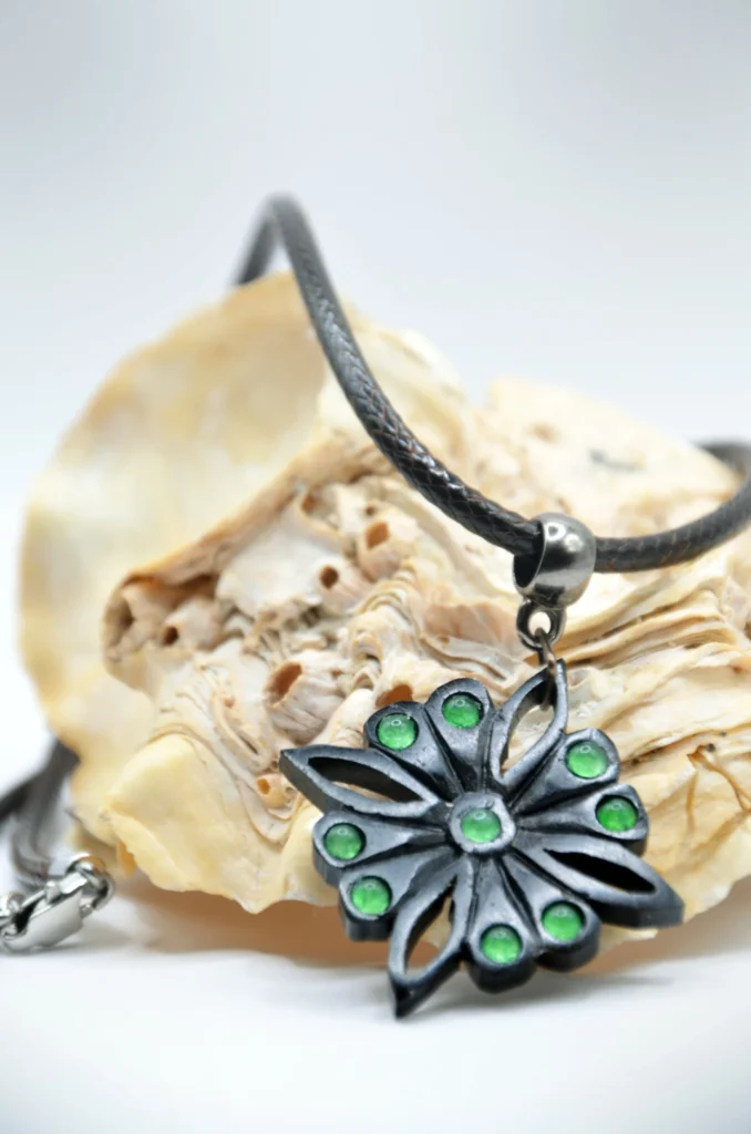 Collier artisanal en bois d’ébène noir et pierre de jade vert, inspiré des motifs floraux sassanides de Taq-e Bostan.