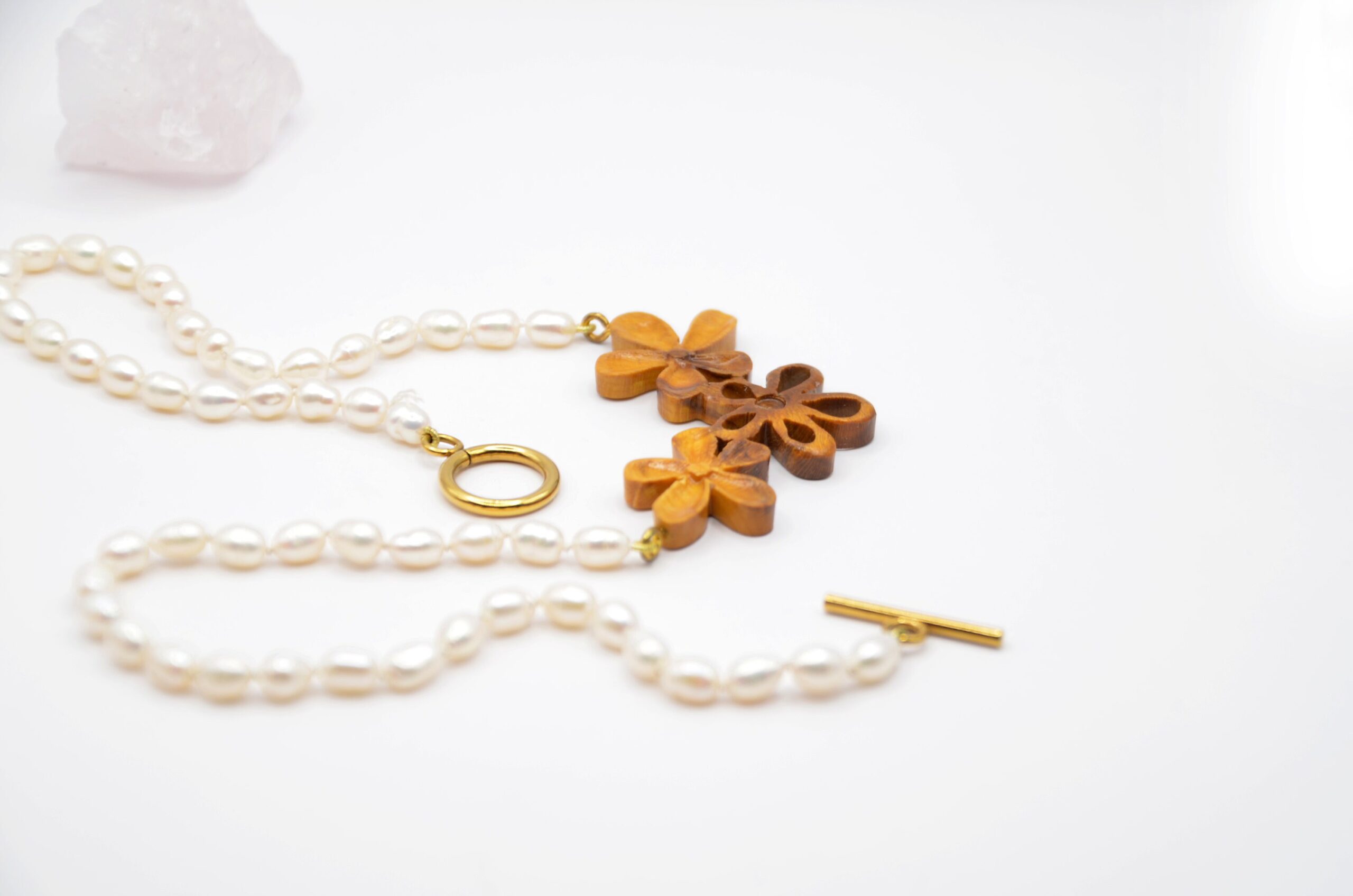 Collier artisanal en bois de berbéris bicolore sculpté de trois fleurs, monté sur un cordon de perles nouées à la main.