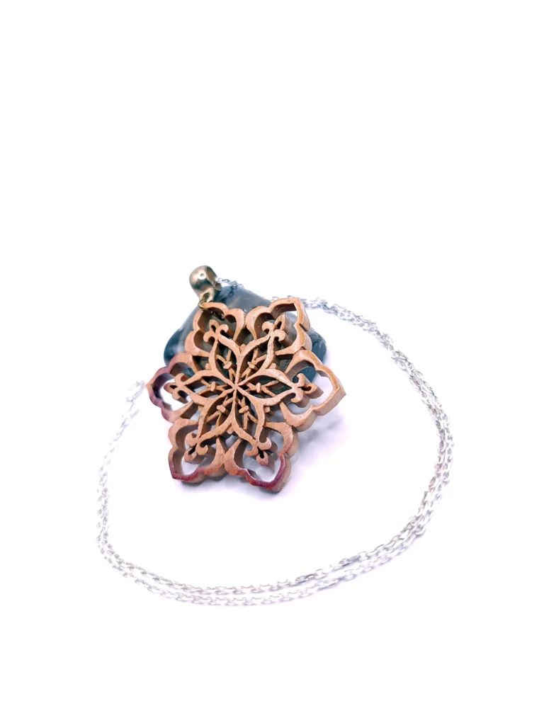 Collier artisanal en bois de rose sculpté avec un motif de flocon de neige, réalisé avec une découpe très précise.