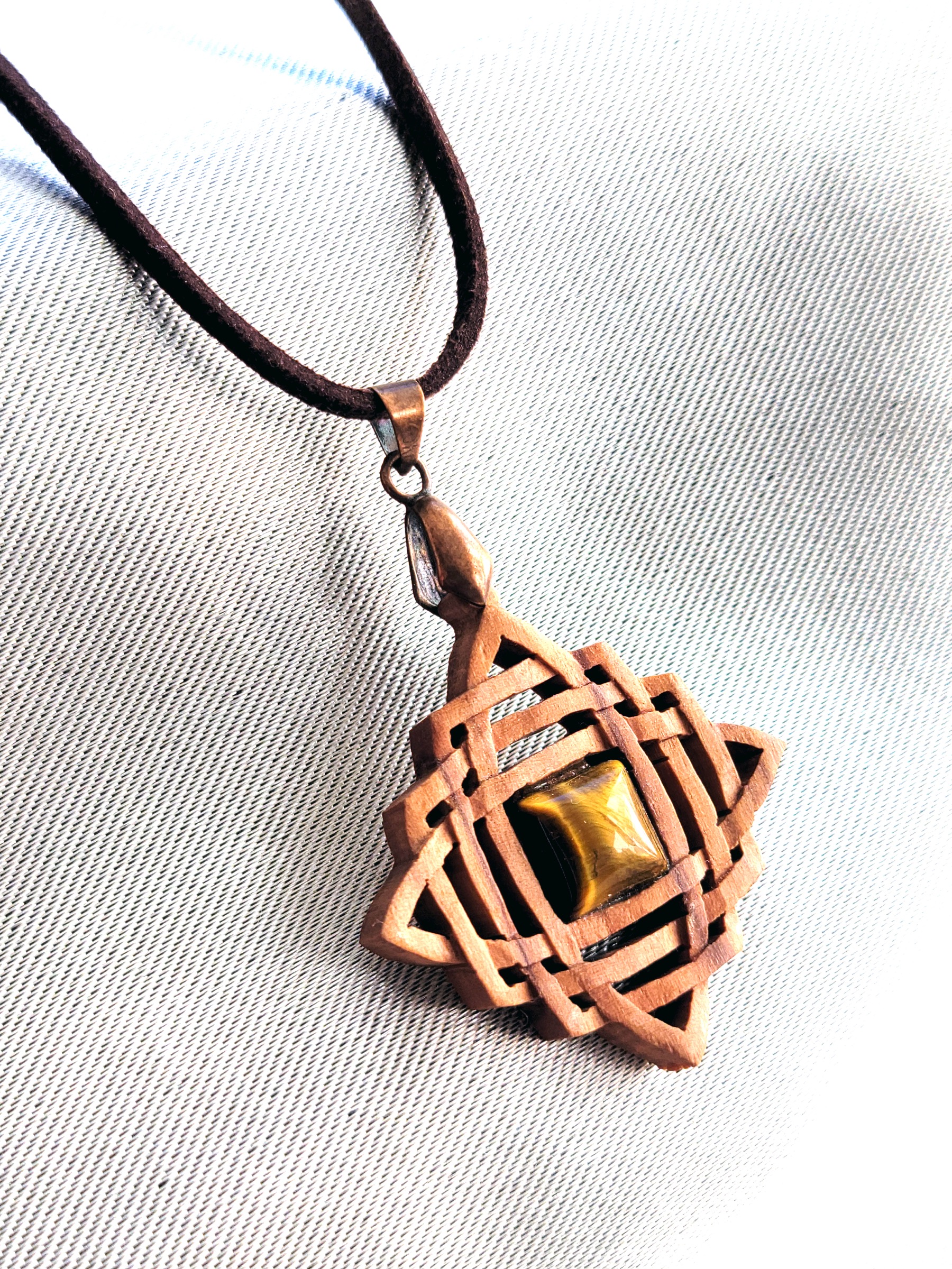Collier artisanal en bois d’olivier et pierre d’œil de tigre, inspiré des motifs celtiques.